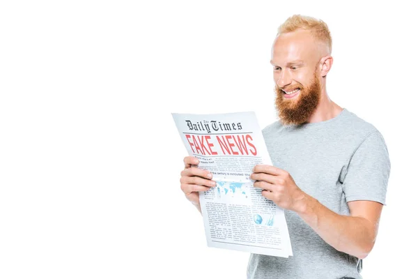 Alegre hombre leyendo el periódico con noticias falsas, aislado en blanco - foto de stock