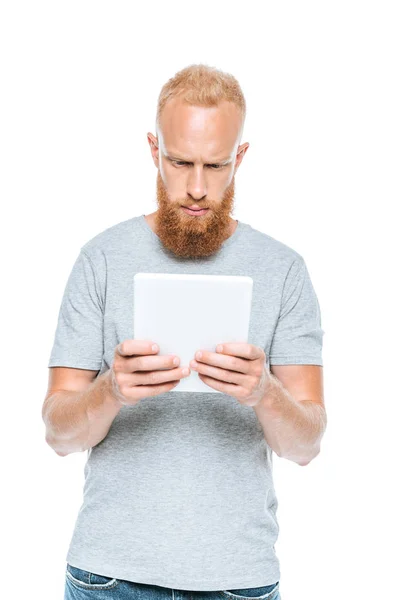 Серьезный бородатый человек с помощью цифровой таблетки, изолированные на белом — стоковое фото