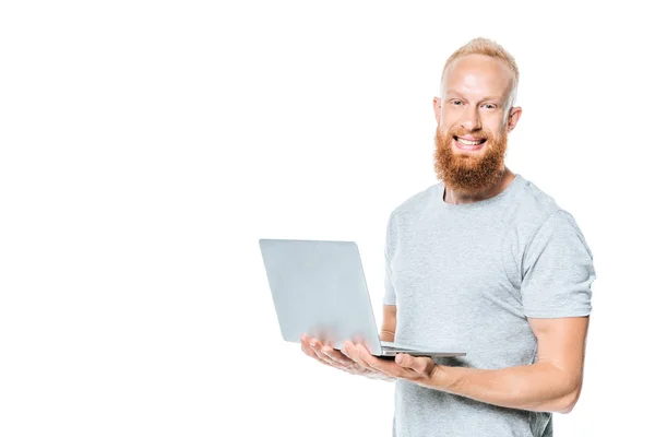 Allegro uomo barbuto che tiene il computer portatile, isolato su bianco — Foto stock