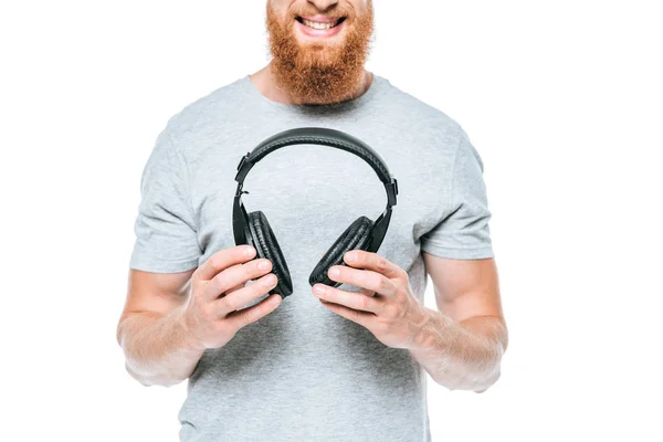 Обрізаний вид усміхненої бороди людини, що тримає навушники, ізольовані на білому — стокове фото