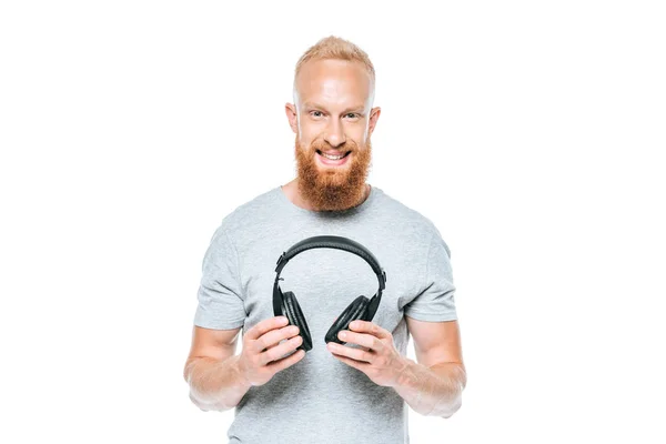 Веселий бородатий чоловік тримає навушники, ізольований на білому — стокове фото