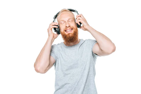 Barba soñadora hombre con los ojos cerrados escuchando música con auriculares, aislado en blanco - foto de stock