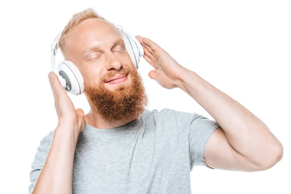 Hombre feliz con los ojos cerrados escuchando música con auriculares, aislado en blanco - foto de stock