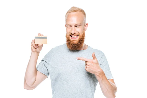 Homem barbudo sorridente apontando para o cartão de crédito, isolado em branco — Fotografia de Stock