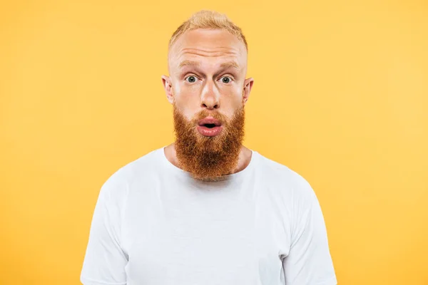 Portrait of surprised handsome bearded man looking at camera, isolated on yellow — Stock Photo