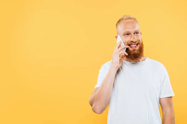 Homem barbudo feliz falando no smartphone, isolado no amarelo — Fotografia de Stock