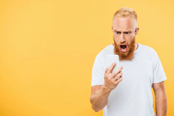 Sorprendido hombre gritando en el teléfono inteligente, aislado en amarillo - foto de stock