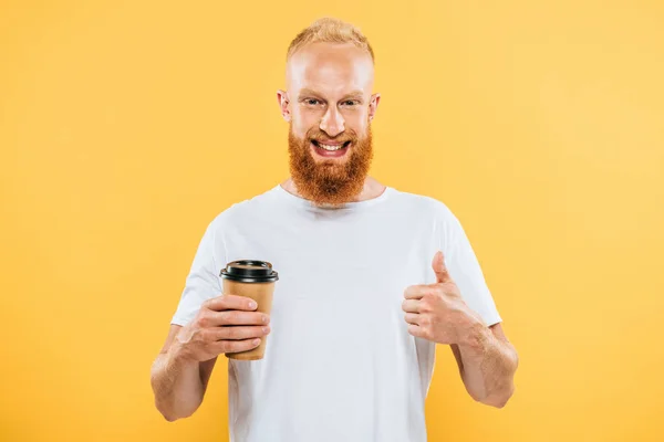 Happy bearded man in t-shirt showing thumb up and holding coffee to go, isolated on yellow — Stock Photo