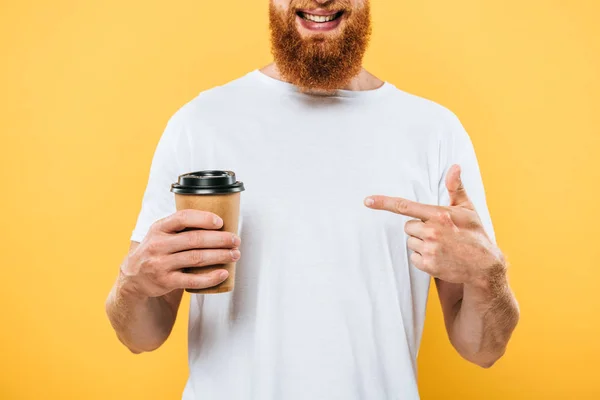 Cropped view of smiling man pointing at coffee to go, isolated on yellow — Stock Photo