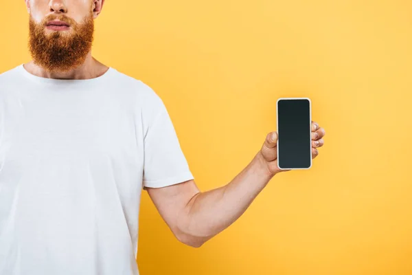 Vista recortada del hombre que muestra el teléfono inteligente con pantalla en blanco, aislado en amarillo - foto de stock