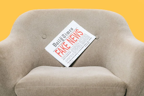 Giornale con notizie false sulla poltrona, isolato sul giallo — Foto stock