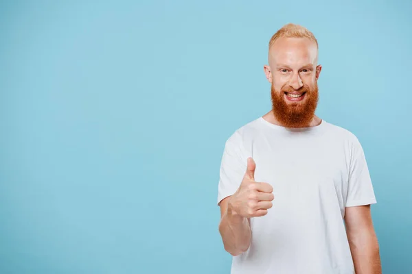 Ritratto di uomo barbuto allegro in t-shirt bianca che mostra pollice in su, isolato su blu — Foto stock