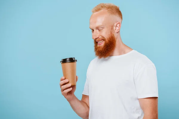 Homme barbu gai en t-shirt à la recherche de café à emporter, isolé sur bleu — Photo de stock