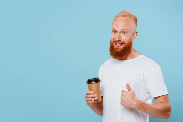 Homem barbudo em t-shirt mostrando polegar para cima com café para ir, isolado em azul — Fotografia de Stock