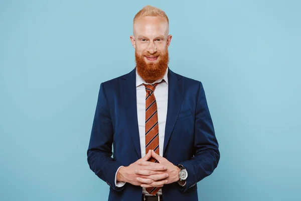 Sonriente hombre de negocios barbudo en traje, aislado en azul - foto de stock