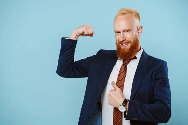 Smiling strong bearded businessman in suit, isolated on blue — Stock Photo
