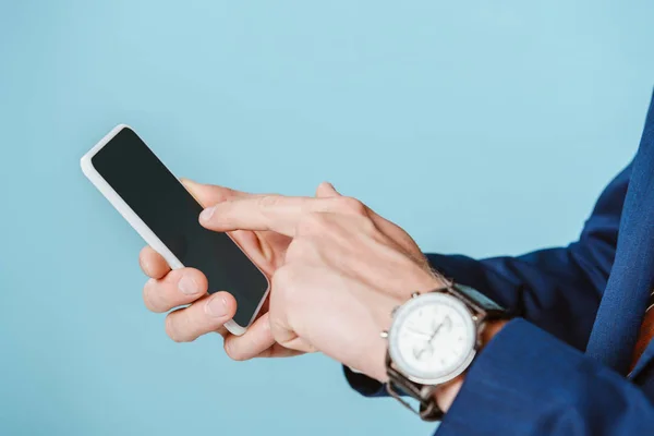 Vue recadrée de l'homme d'affaires avec montre bracelet à l'aide d'un smartphone, isolé sur bleu — Photo de stock
