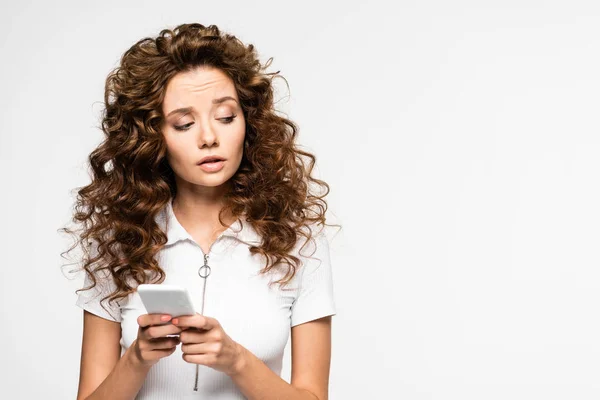 Thoughtful curly girl using smartphone, isolated on white — Stock Photo