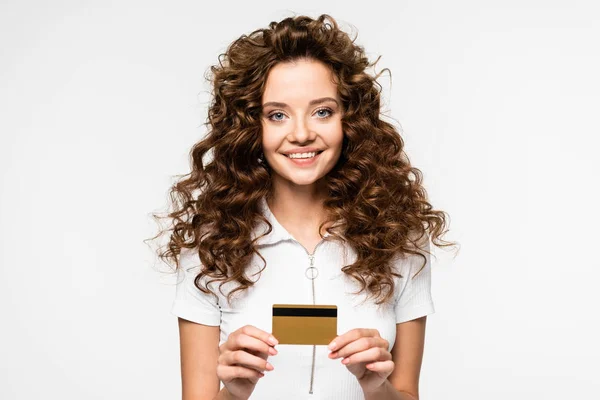 Красива кучерява молода жінка тримає кредитну картку, ізольована на білому — стокове фото