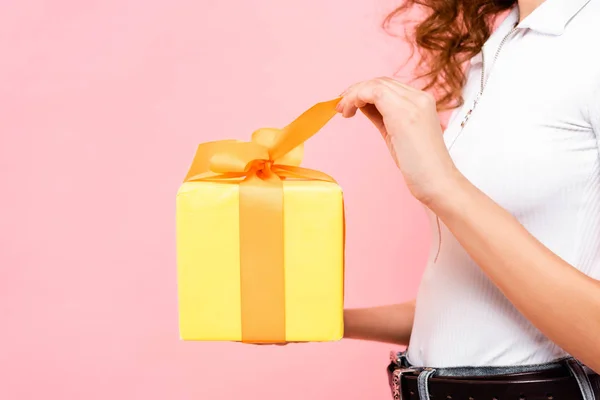 Vista ritagliata di ragazza in possesso di regalo giallo, isolato su rosa — Foto stock