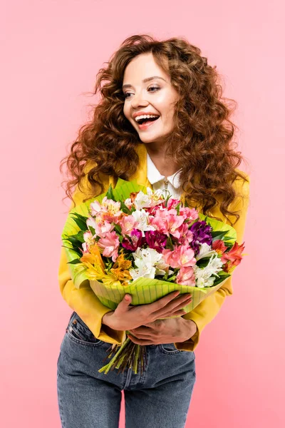 Hermosa chica feliz sosteniendo ramo de flores, aislado en rosa - foto de stock