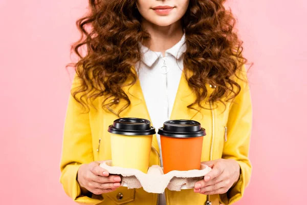 Cropped view of curly woman holding paper cups with coffee, isolated on pink — Stock Photo