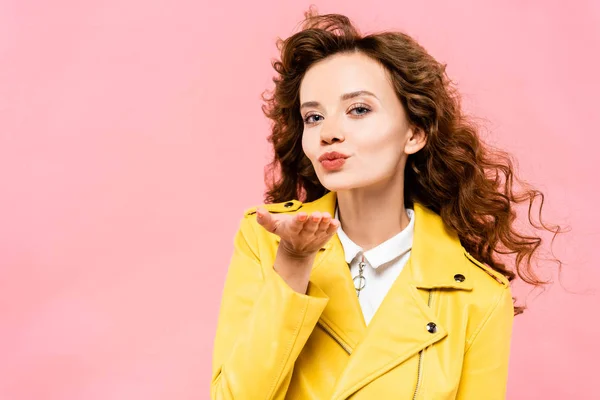 Glückliches Mädchen in gelber Lederjacke bläst Luftkuss, isoliert auf rosa — Stockfoto