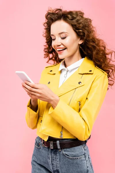 Chica rizada feliz usando teléfono inteligente, aislado en rosa - foto de stock