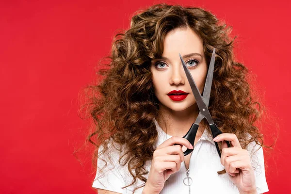 Menina encaracolado atraente segurando tesoura, isolado em vermelho — Fotografia de Stock