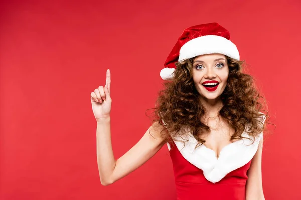 Menina feliz em Santa traje apontando para cima, isolado em vermelho — Fotografia de Stock