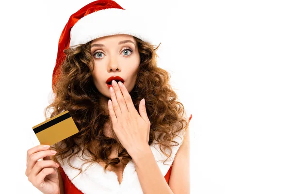 Femme choquée en costume de Père Noël et chapeau tenant carte de crédit, isolé sur blanc — Photo de stock