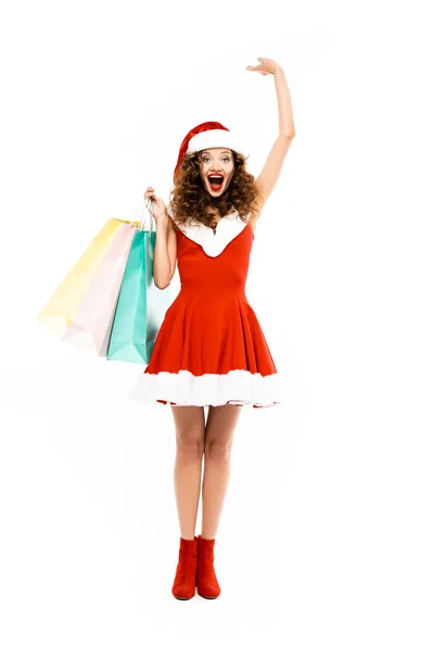 Belle femme excitée en costume de Père Noël posant avec des sacs à provisions, isolé sur blanc — Photo de stock