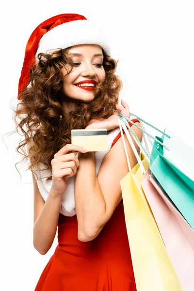 Hermosa chica sonriente en traje de santa celebración de bolsas de compras y tarjeta de crédito, aislado en blanco - foto de stock