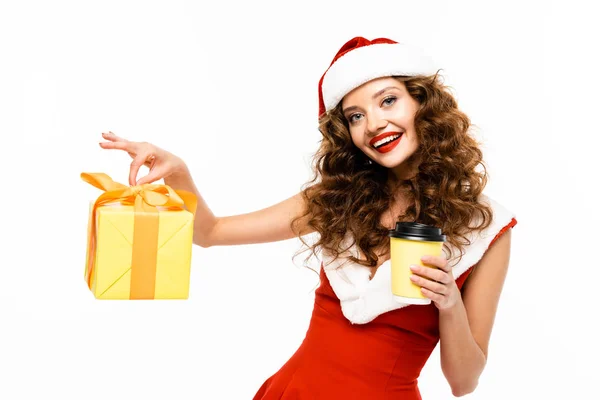 Sorridente ragazza in costume da Babbo Natale in possesso di regalo di Natale e caffè da andare, isolato su bianco — Foto stock