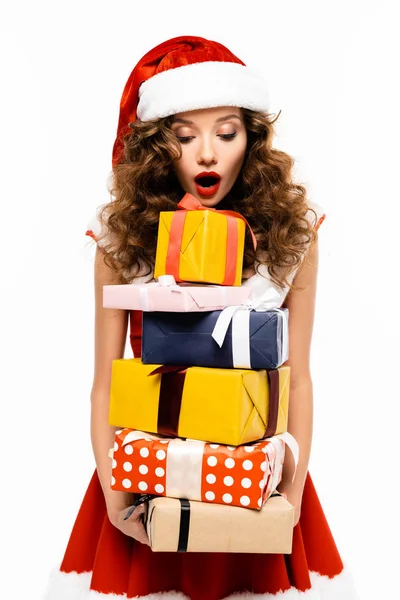 Shocked girl in santa costume holding pile of gifts, isolated on white — Stock Photo