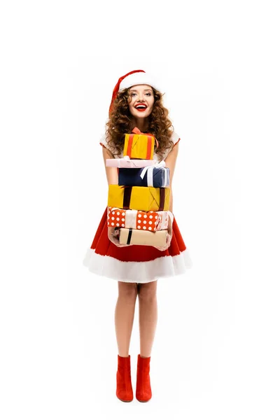 Щаслива дівчина в костюмі Санти тримає стек подарунків, ізольована на білому — стокове фото