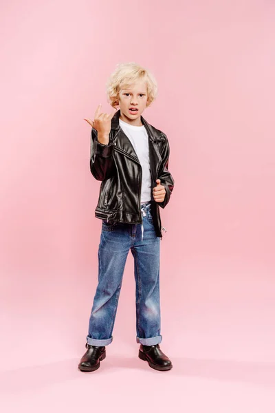 Enfant en veste en cuir montrant signe de roche sur fond rose — Photo de stock