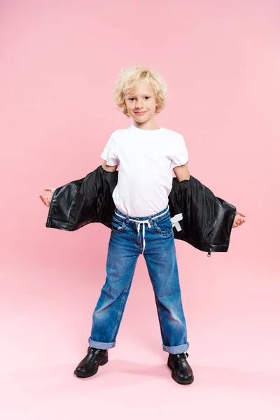 Lächelndes Kind in Lederjacke blickt in die Kamera auf rosa Hintergrund — Stockfoto