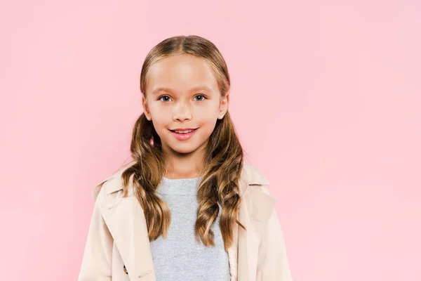 Enfant souriant en manteau regardant la caméra isolée sur rose — Photo de stock