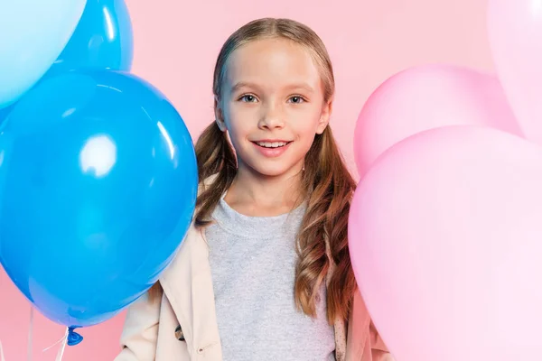 Lächelndes Kind im Herbst-Outfit mit Luftballons auf rosa — Stockfoto