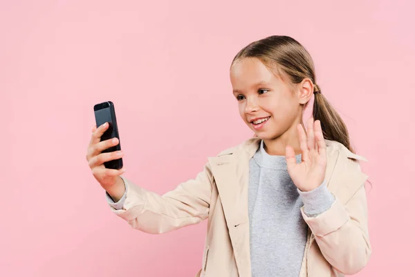 Lächelndes und süßes Kind winkt während Videochat isoliert auf rosa — Stockfoto