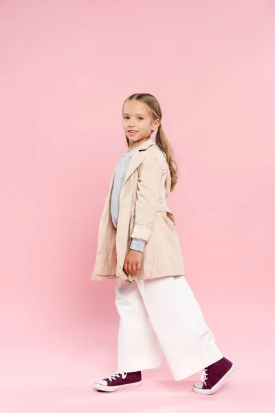 Lächelndes Kind im Herbst-Outfit mit Blick in die Kamera auf rosa Hintergrund — Stockfoto
