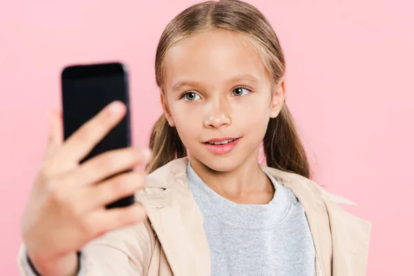 Selektiver Fokus eines lächelnden Kindes, das ein Selfie isoliert auf rosa macht — Stockfoto