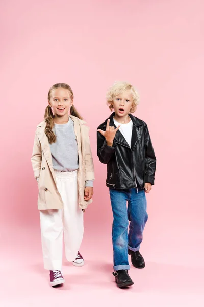 Enfants souriant et montrant signe de roche sur fond rose — Photo de stock