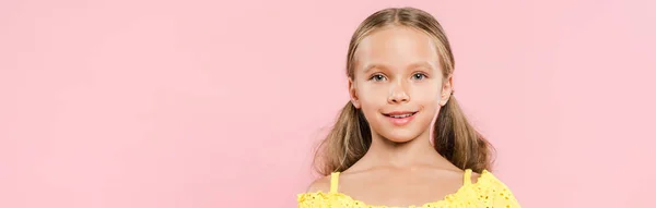 Панорамный снимок улыбающегося ребенка, смотрящего на камеру, изолированную на розовом — стоковое фото