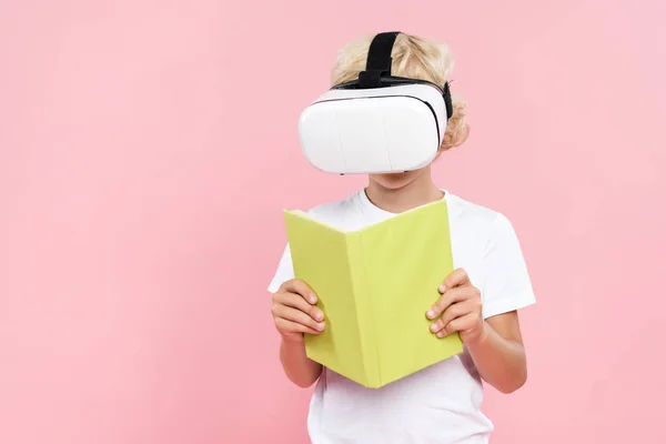 Kind mit Virtual-Reality-Headset liest Buch isoliert auf rosa — Stockfoto