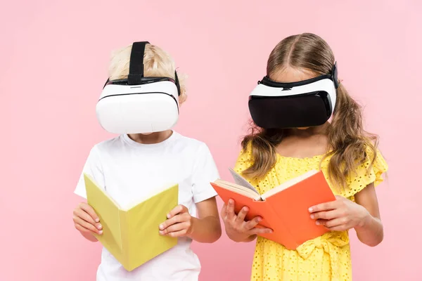 Niños con libro de lectura de auriculares de realidad virtual aislados en rosa - foto de stock