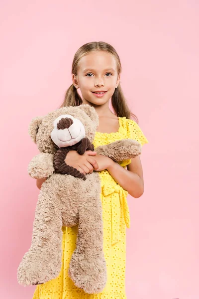 Smiling and cute kids holding teddy bear isolated on pink — Stock Photo