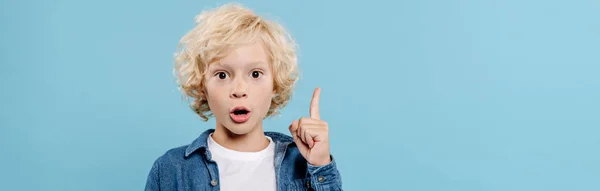 Panoramic shot of shocked and cute kid showing idea sign isolated on blue — Stock Photo