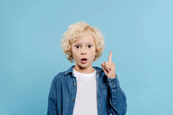 Schockiertes und süßes Kind zeigt Ideenschild auf blauem Grund — Stockfoto